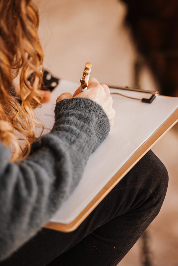 Eine Frau schreibt konzentriert auf einem Klemmbrett.